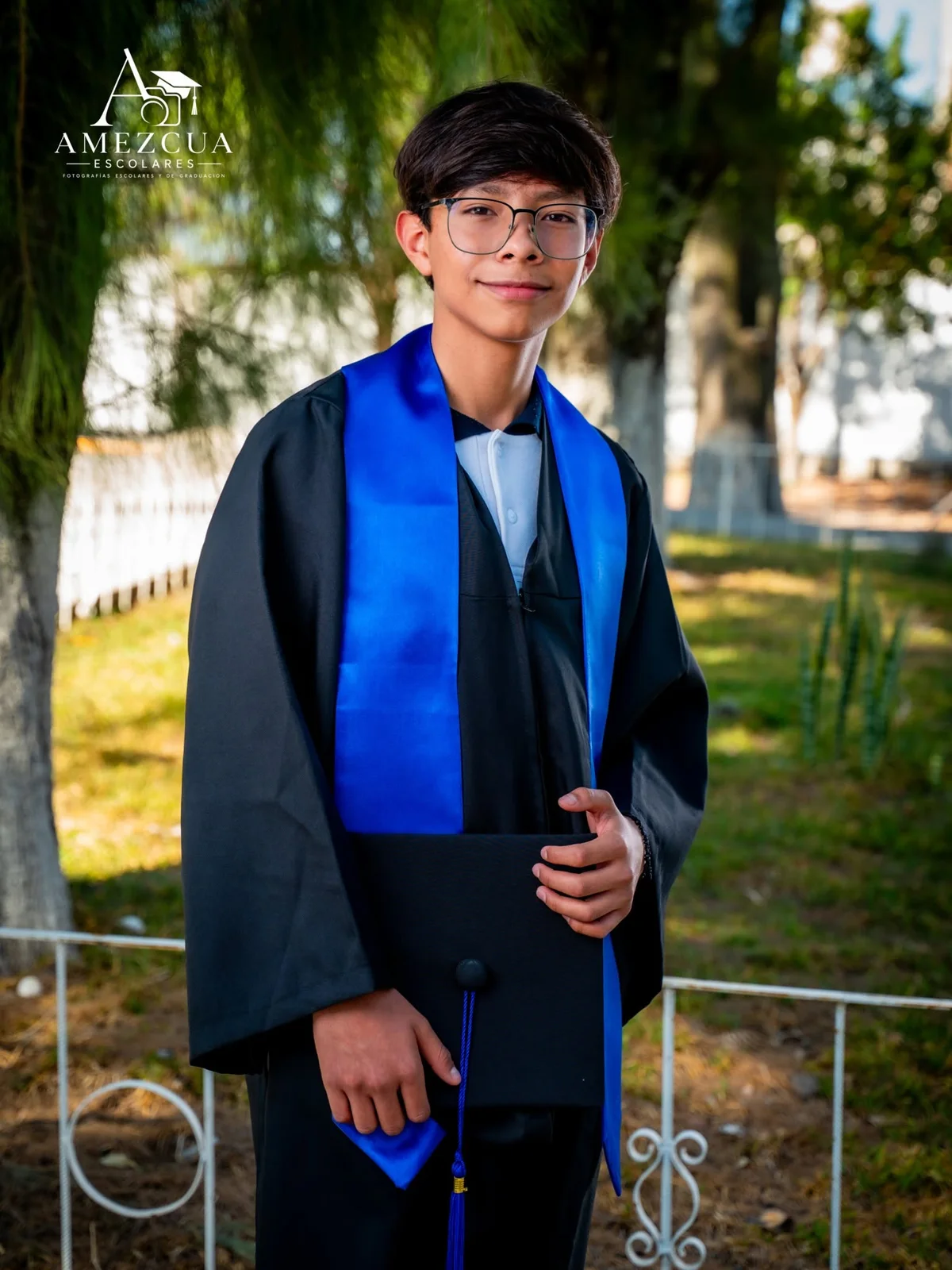 Retrato de graduado con estola azul en un jardín